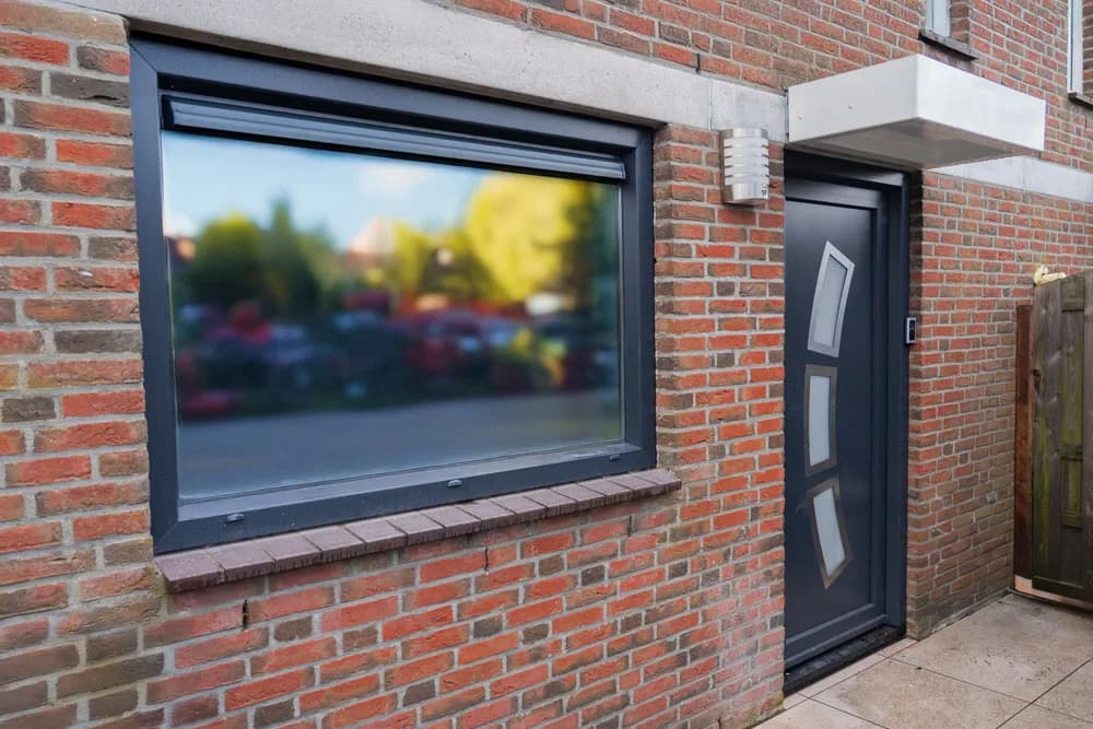 Klassieke voordeur wit kunststof met panelen in bakstenen gevel